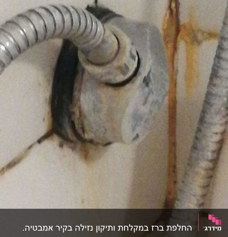 צינור מתכת מחובר לקיר עם חלודה